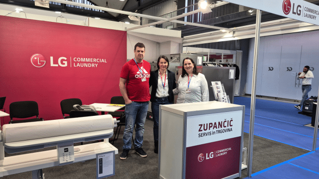 LG Commercial Laundry exhibition stand at GAST Ljubljana showcasing professional washers, dryers, and finishing equipment, with team members and visitors engaging in technical discussions.